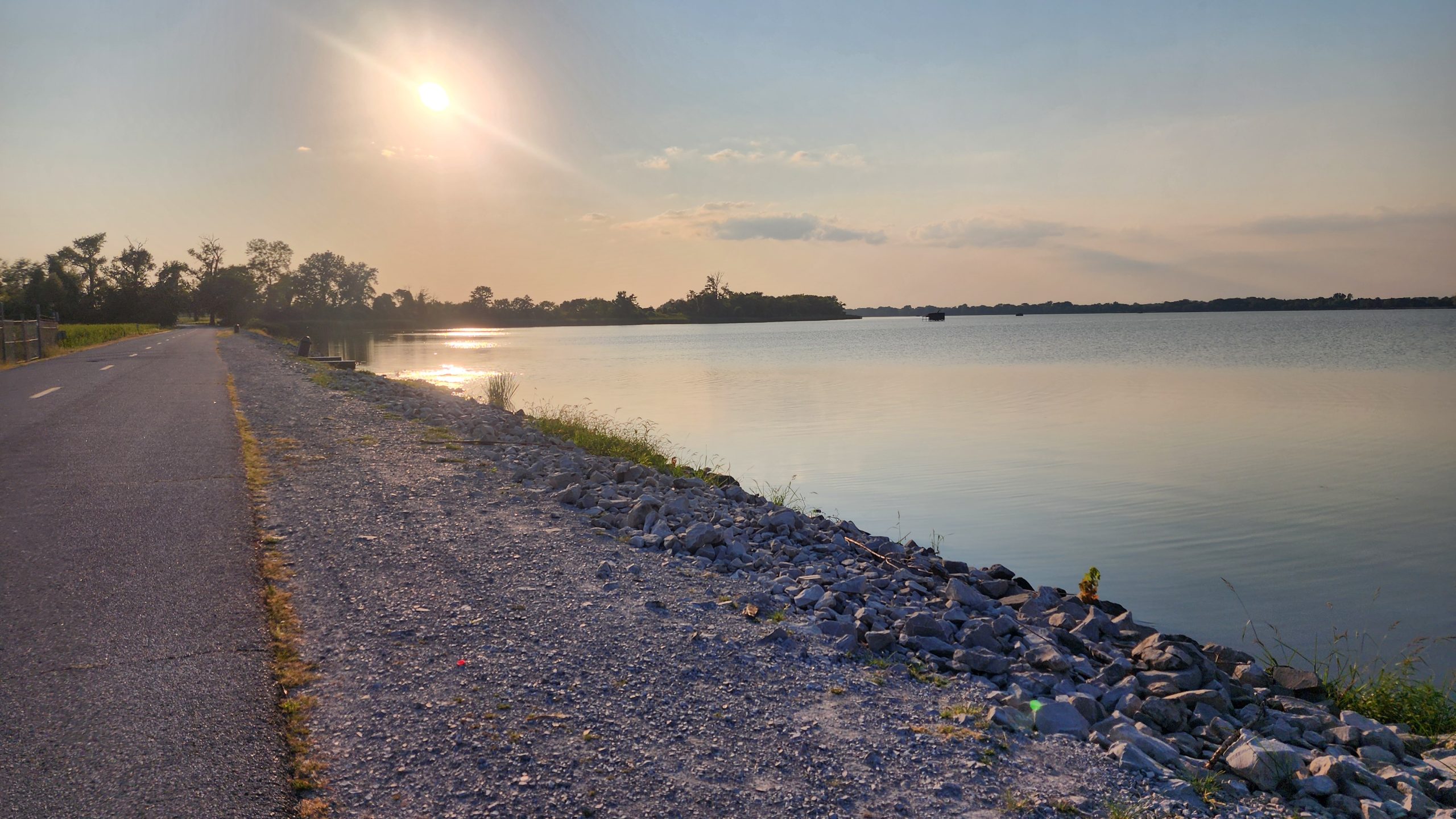 Sunset over a reservoir in southern Illinois, gravel path leading forward along the water.