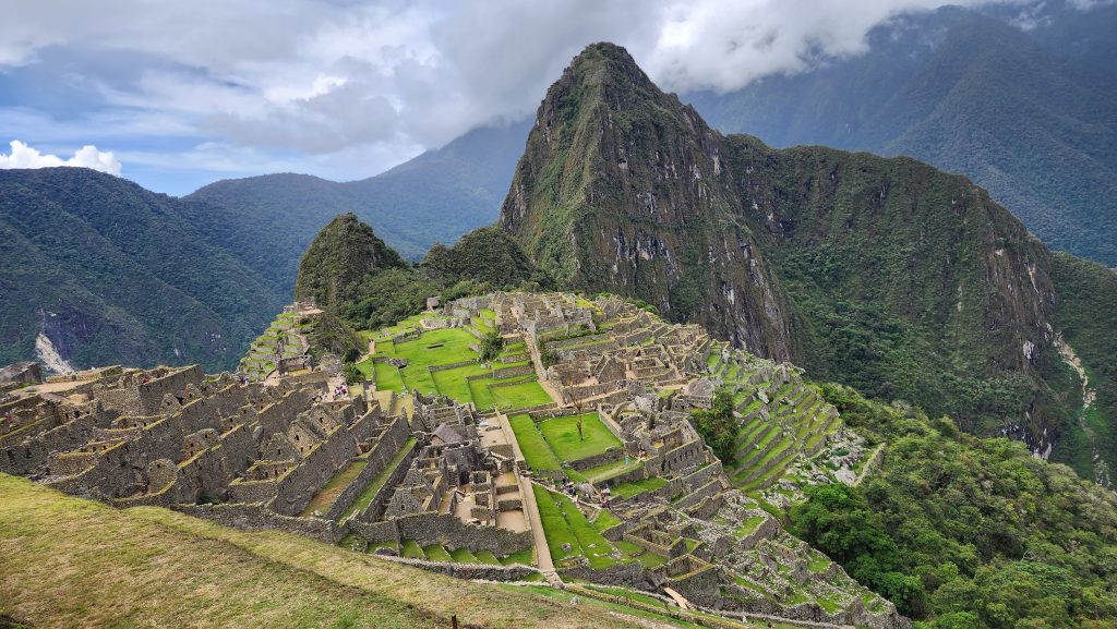 Machu Picchu citadel with clouds wrapping Huayna Picchu peak and stone terraces descending the mountainside