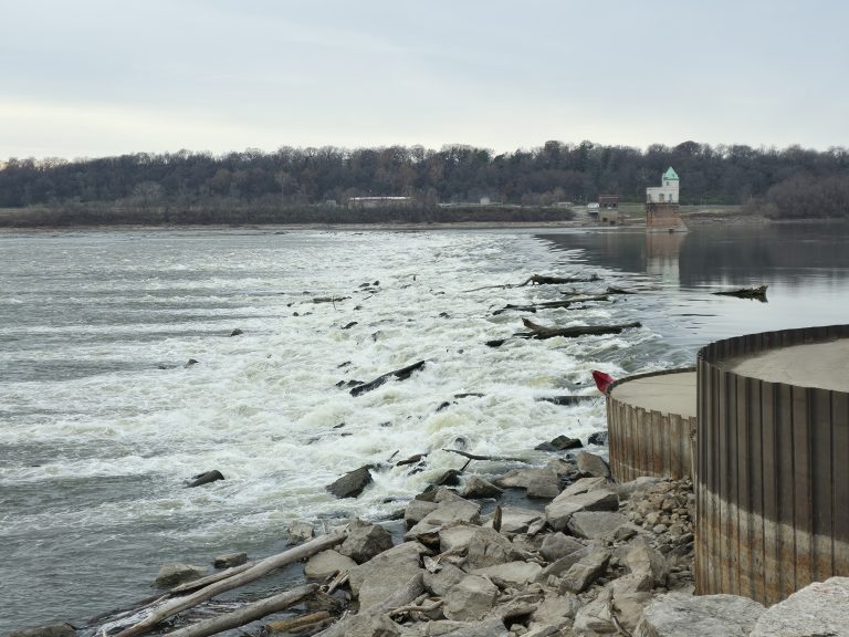 Mississippi River churning against the weathered steel of the Chain of Rocks Bridge under a gray winter sky.