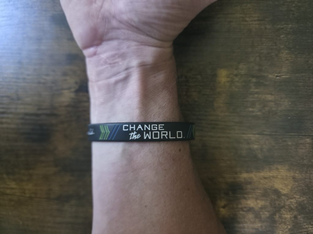 A silicone bracelet worn on the wrist, the band's edges smoothed and the lettering faded with use.