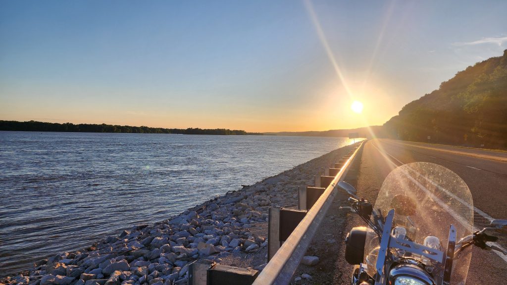View down the Great River Road at sunset from a parked motorcycle, Mississippi River on the left and limestone bluffs on the right