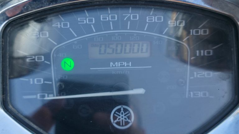 Motorcycle odometer showing 50,000 miles, photographed in a parking lot